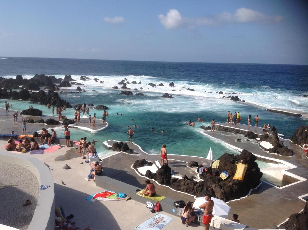 a group of people in the water at the beach at Pensão Fernandes in Porto Moniz