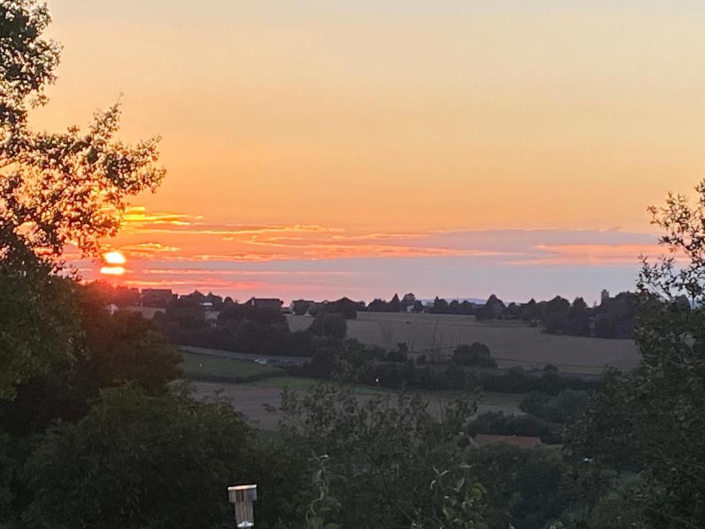 a sunset over a field with the sun setting at Ferienwohnung Julia in Vlotho