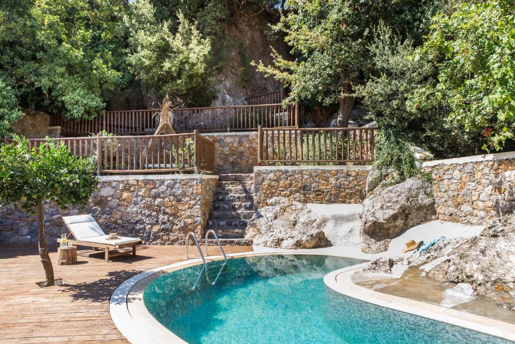 une piscine dans une arrière-cour avec un mur en pierre dans l'établissement Villa Angelica Meronas, à Méronas