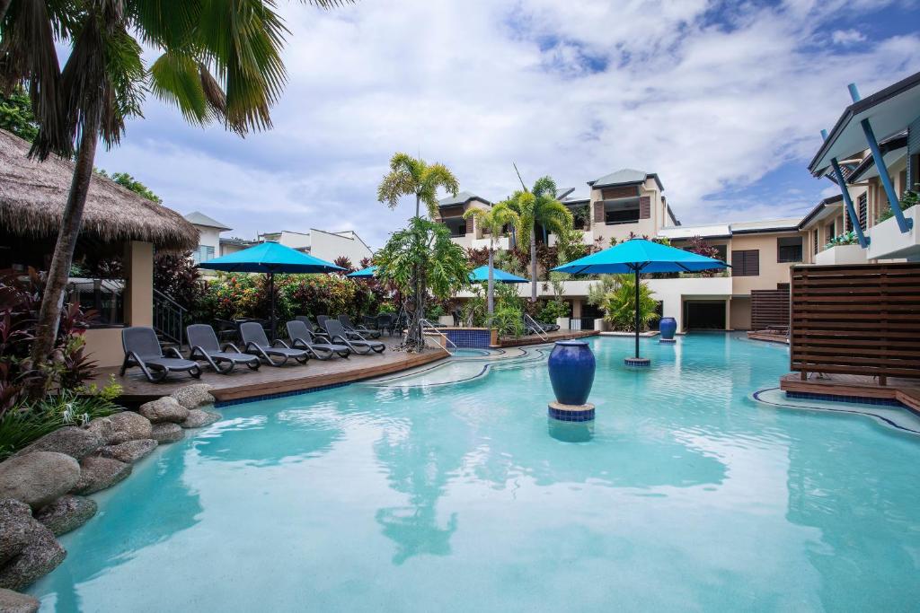 einen Pool mit Stühlen und Sonnenschirmen in einem Resort in der Unterkunft Mantra Heritage in Port Douglas