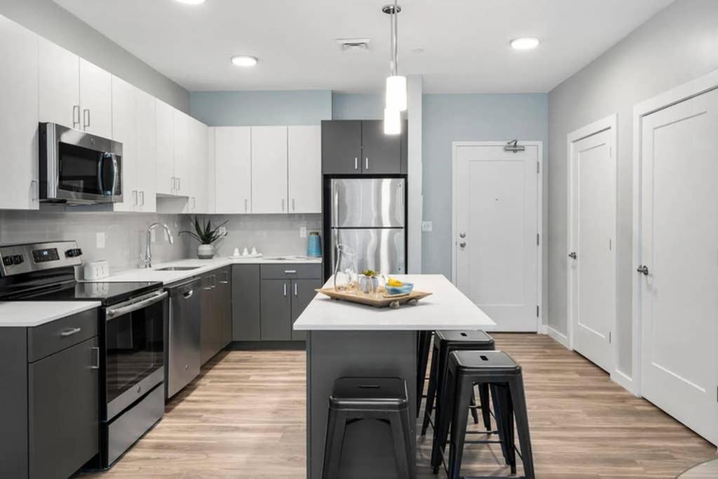 a kitchen with white cabinets and a kitchen island with stools at Luxury Apartment with Gym, Steps From Commuter Rail #3013 in Reading