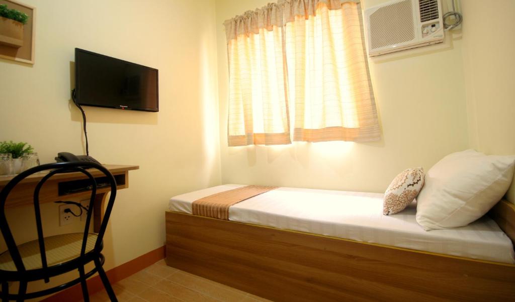 a bedroom with a bed with a television and a chair at Anri Pension House in Cebu City