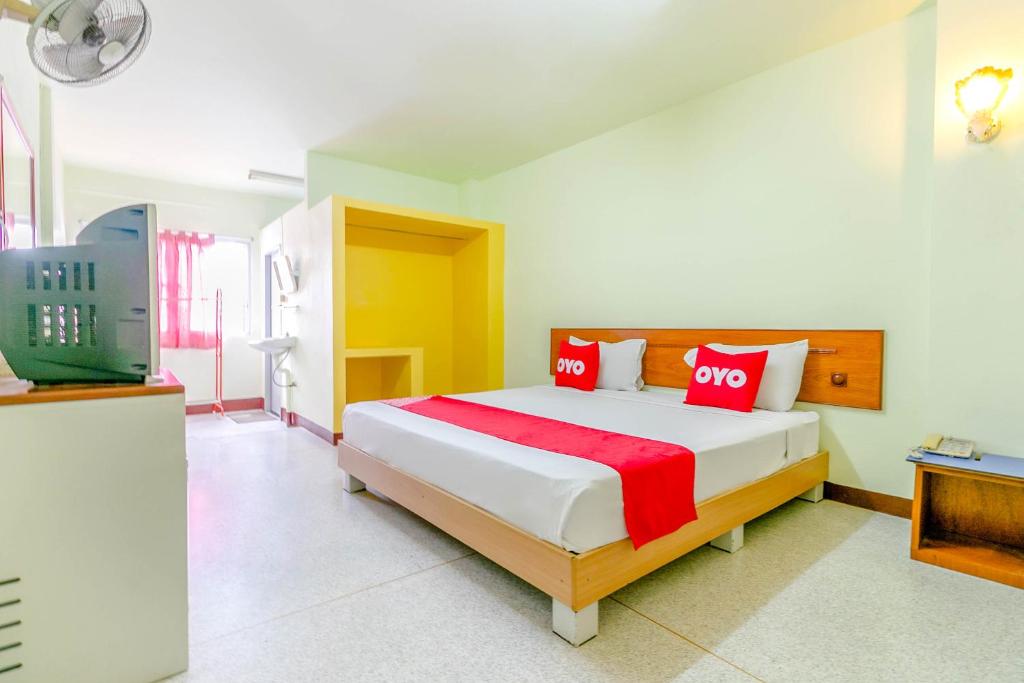 a bedroom with a bed with red pillows and a tv at OYO 1161 Sathorn Mansion in Nakhon Ratchasima