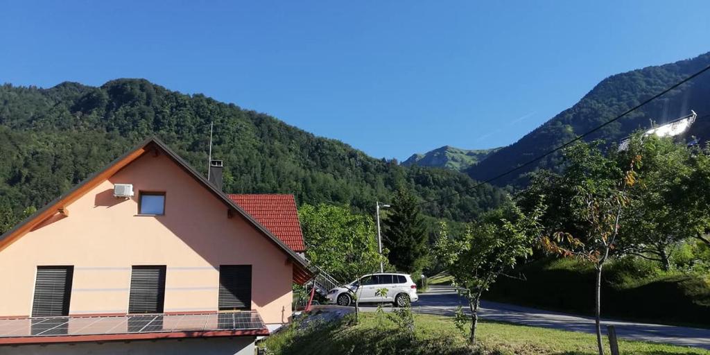 a car parked next to a house with mountains in the background at Apartments Laznica in Cerkno