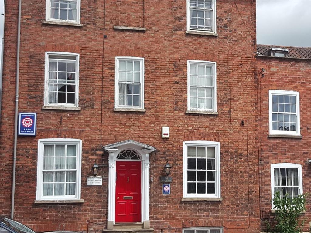 un bâtiment en briques rouges avec une porte rouge dans l'établissement The Red House, à Grantham