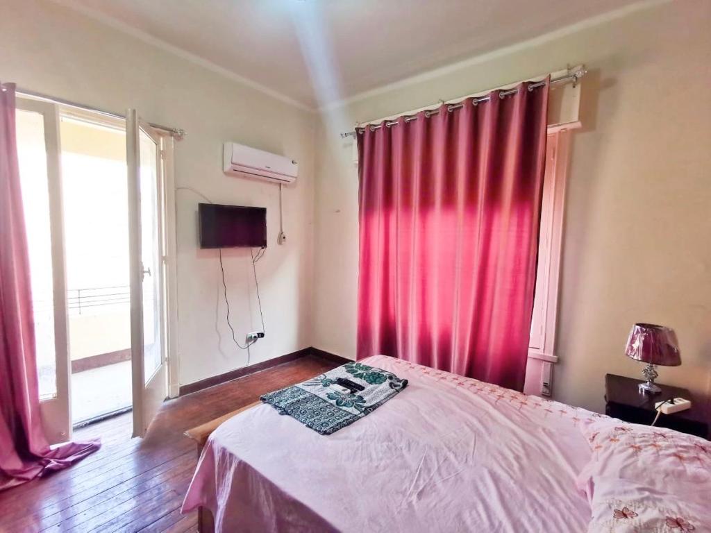 een slaapkamer met een bed en een raam met rode gordijnen bij Joya Apartmento in Caïro