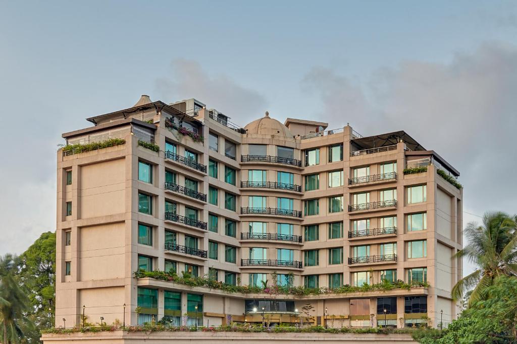 ein hohes, braunes Gebäude mit Fenstern und Palmen in der Unterkunft Goldfinch Hotel Mangalore in Mangaluru