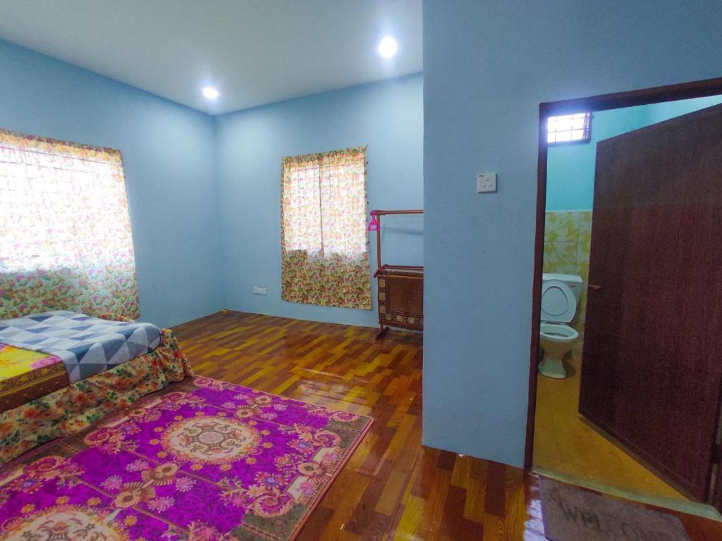 a bedroom with a bed and a toilet and blue walls at Teratak Aqish, Besut Terengganu in Kampong Gong Pauh