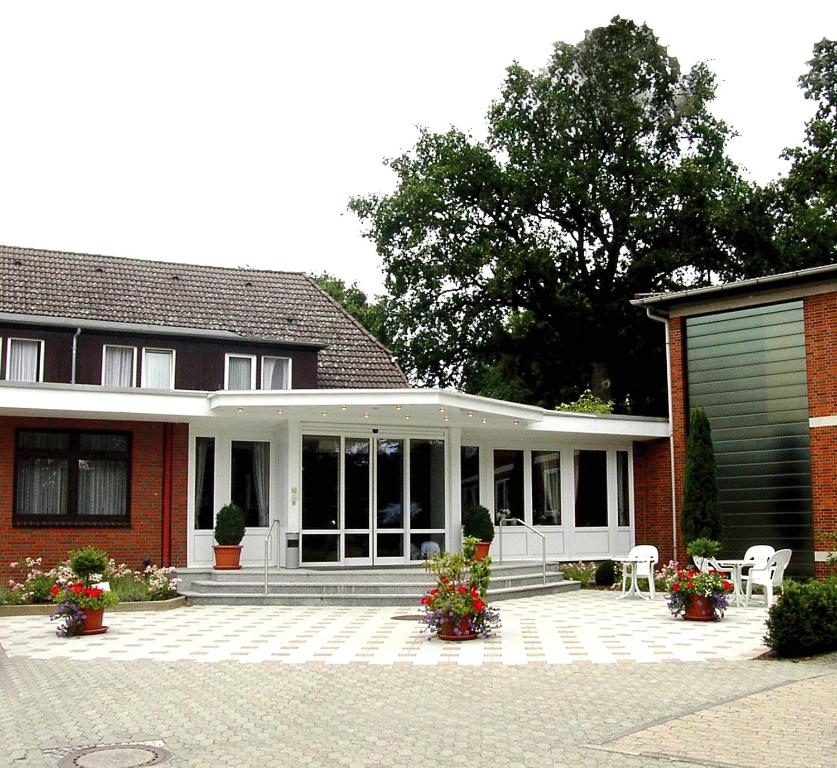 ein rotes Backsteinhaus mit einer Veranda und einer Garage in der Unterkunft Schaperkrug in Celle