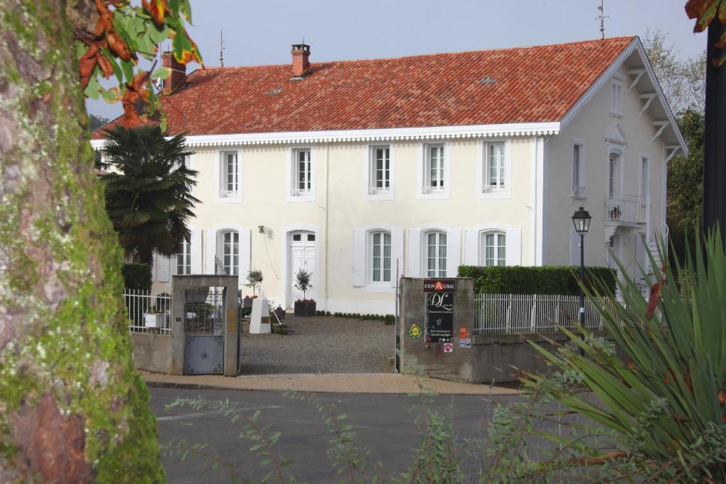 une grande maison blanche avec un toit rouge dans l'établissement Maison d'Hôtes Lassaubatju, à Hontanx