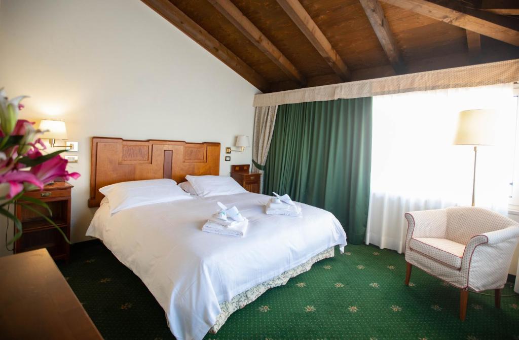 a hotel room with a bed and a chair and a window at Hotel Candiani in Casale Monferrato