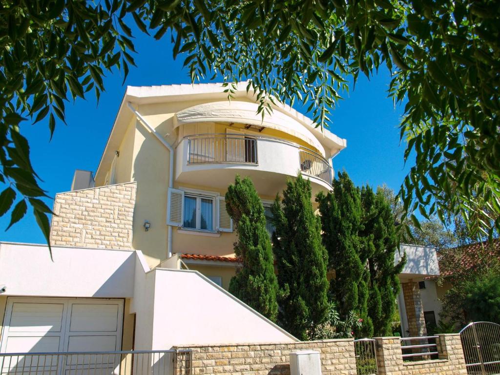une grande maison blanche avec des arbres devant elle dans l&#39;établissement Kristi apartment complex, à Privlaka
