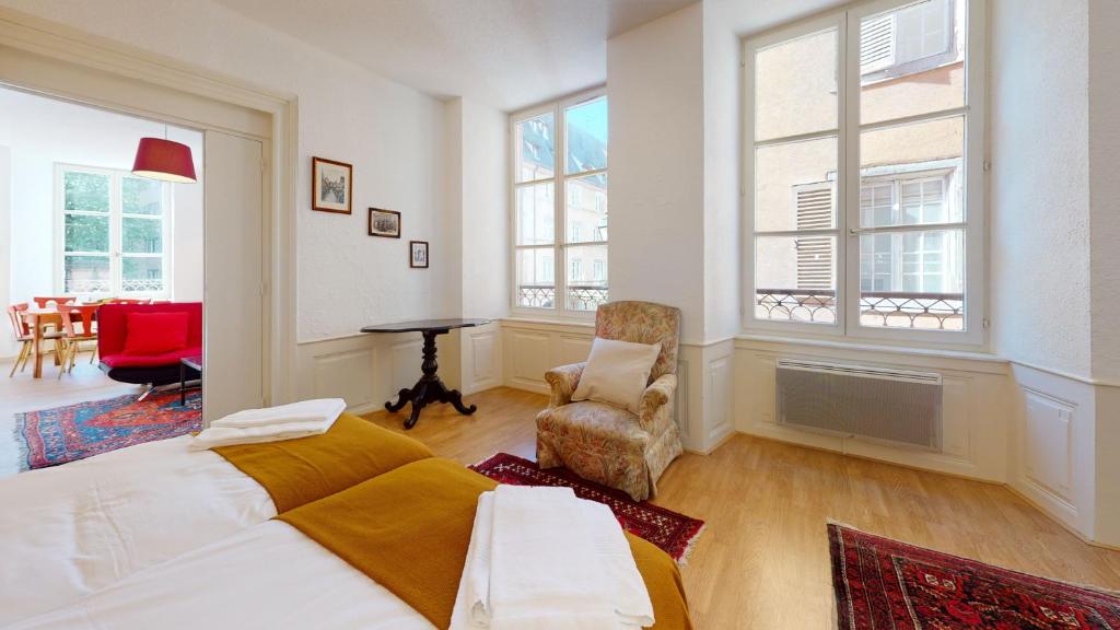 1 dormitorio con 1 cama, 1 silla y ventanas en Chez Gasti, en Colmar