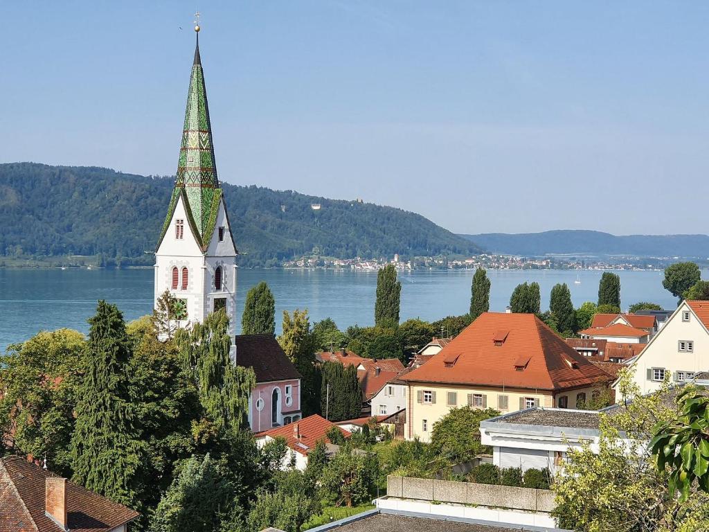 a town with a church with a steeple and a lake at Panorama Seesicht in Sipplingen