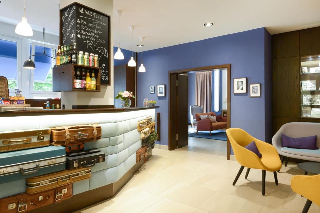 a bar in a restaurant with blue walls and yellow chairs at Hotel Stella Maris in Hamburg