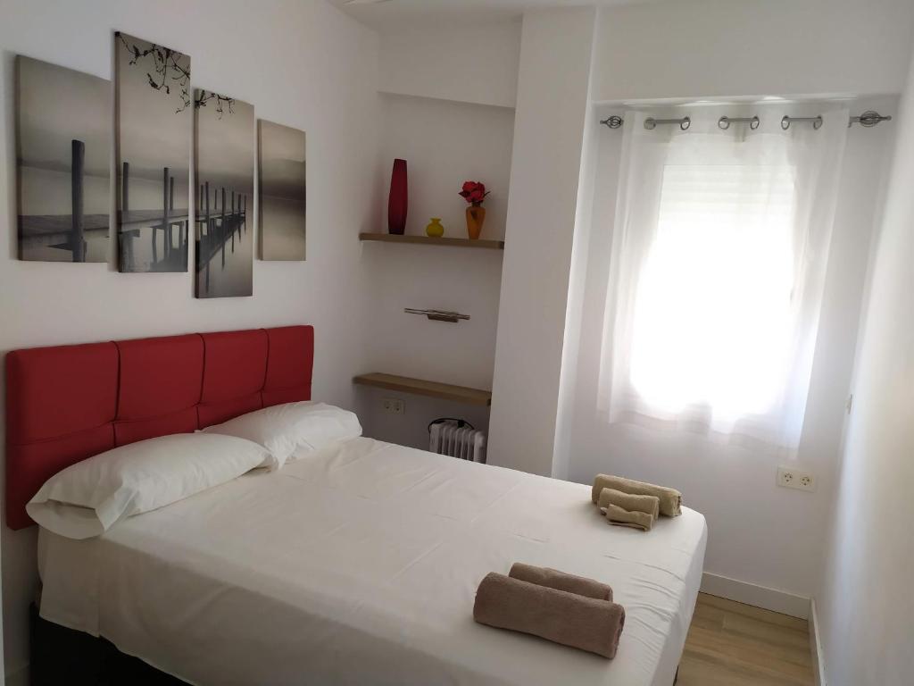 1 dormitorio con 1 cama con cabecero rojo y ventana en Zapillo, en Almería