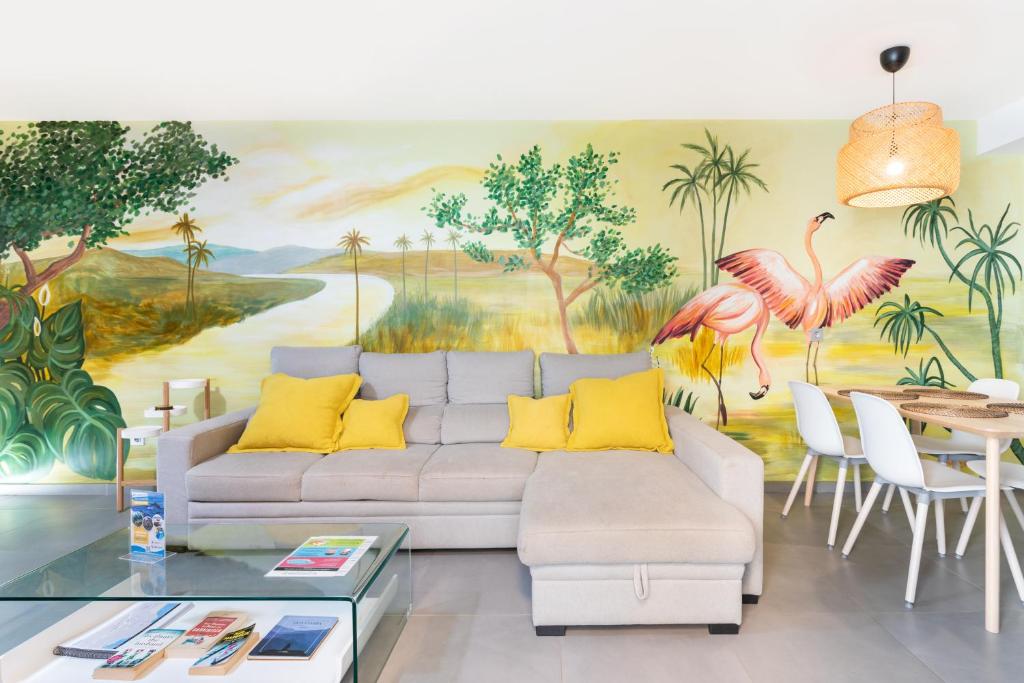una sala de estar con sofá y una pintura de flamencos en Apartamentos Las Terrazas de Sotavento, en La Mareta