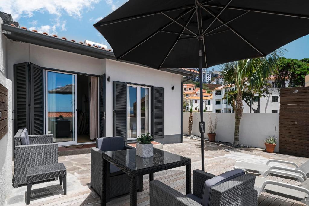 une terrasse avec une table, des chaises et un parasol dans l'établissement Terrace Vila by An Island Apart, à Caniço
