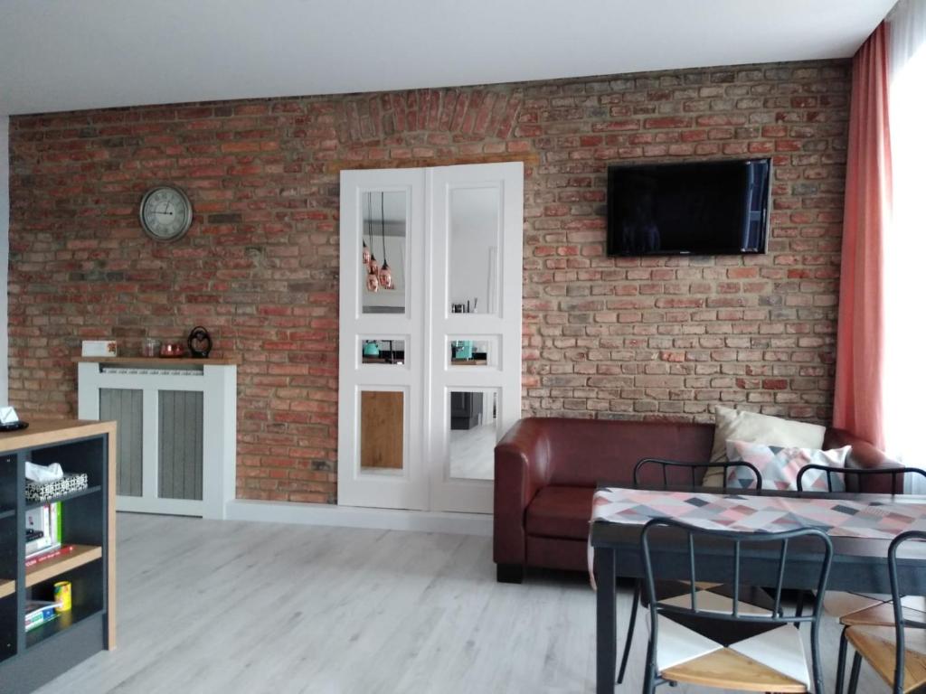 卡利什的住宿－Apartament w kamienicy Przy Plantach，带沙发和砖墙的客厅