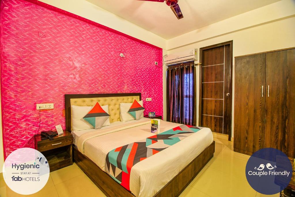 um quarto com uma cama e uma parede rosa em FabExpress T P Suite em Nova Deli
