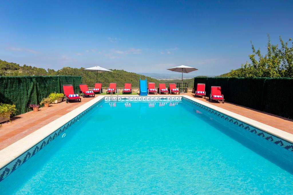 a large swimming pool with red and blue chairs andatoes at 8 to 10 Sleeps Private Pool Villa & BBQ Near Barcelona in Rocafort