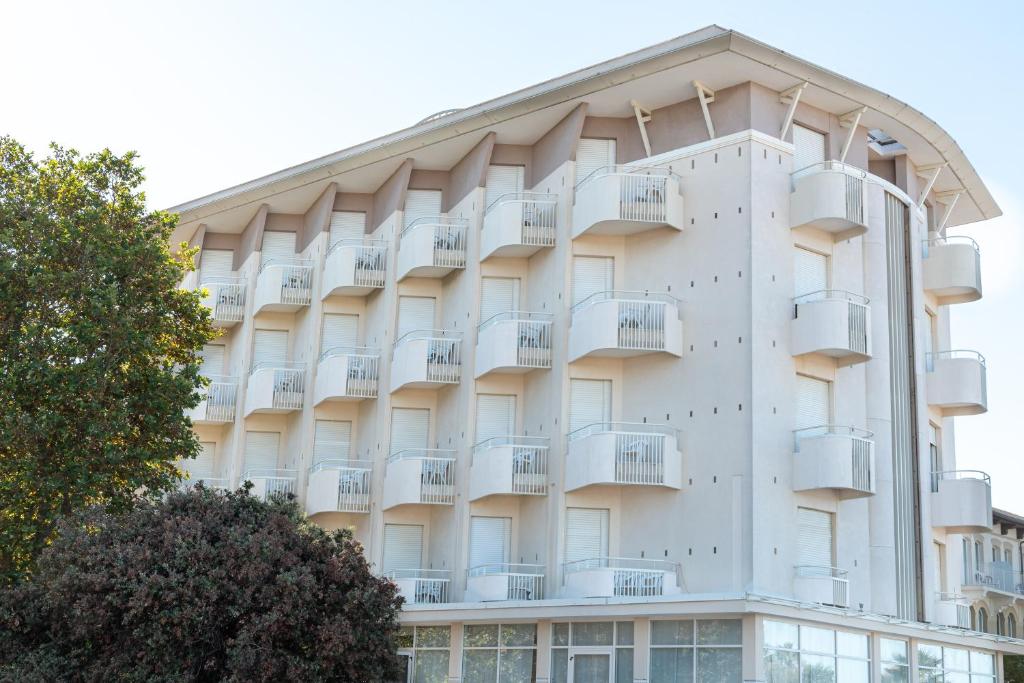 ein weißes Gebäude mit Balkonen darauf in der Unterkunft Hotel Audi Frontemare in Rimini