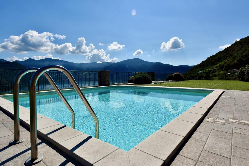 une piscine avec des montagnes en arrière-plan dans l'établissement Italian Vacation Homes - La Petite Maison du Lac, à Tavernola Bergamasca