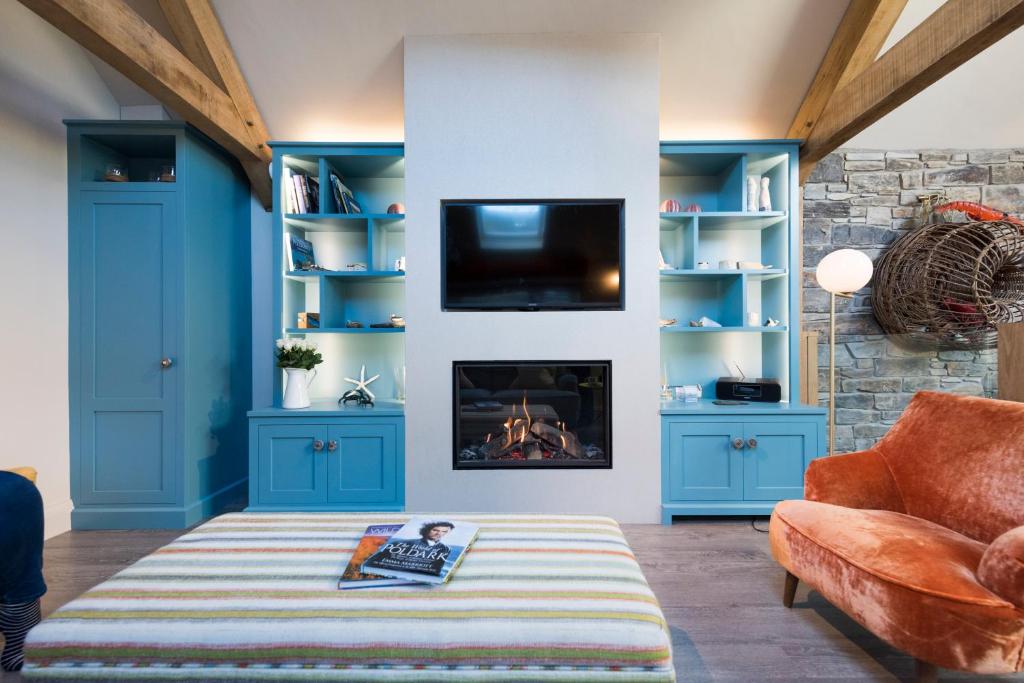 un salon avec des armoires bleues et une cheminée dans l'établissement Wella 5 Star Gold Award Luxury Cottage, à St Ives