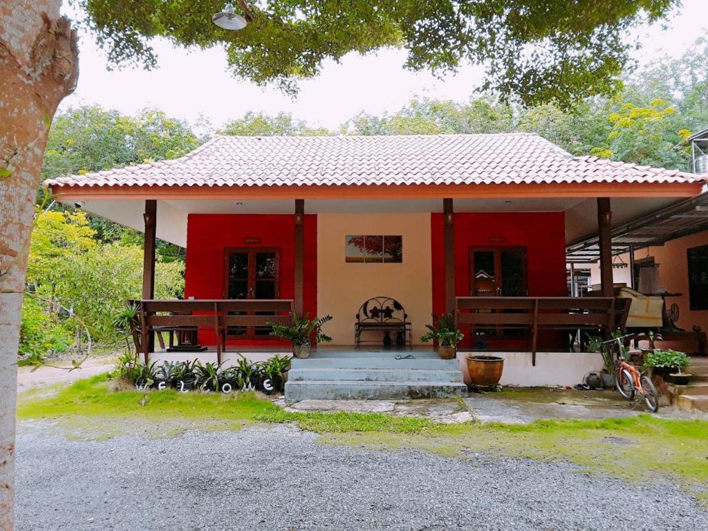 a small red and white house with a porch at Baan Chan Sabai in Chanthaburi