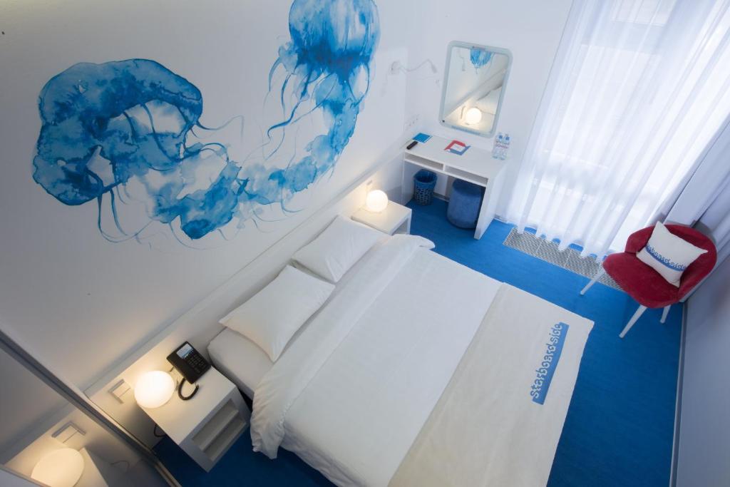 a bedroom with a white bed and blue paint on the wall at Starboard Side Hotel in Moscow