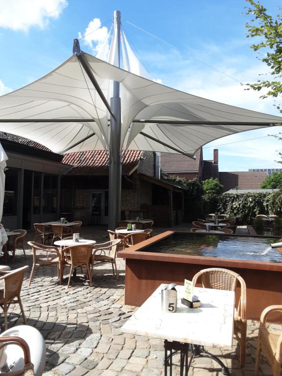 un grande ombrellone bianco su un patio con tavoli e sedie di T Karraet a Maasmechelen