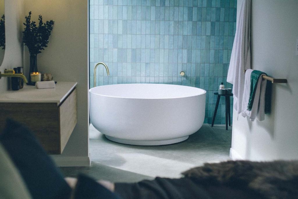 La salle de bains est pourvue d'une baignoire blanche et de carrelage bleu. dans l'établissement Melo Studios, à Dunsborough