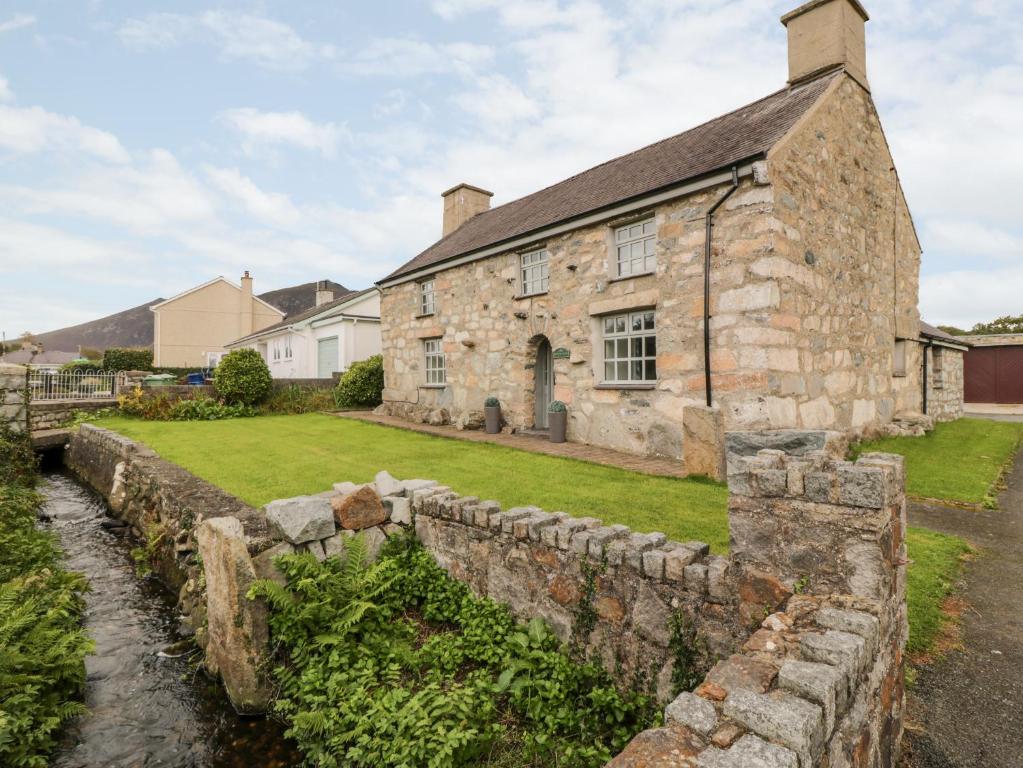 an old stone house with a stone wall at Llwyn Aethnen in Caernarfon