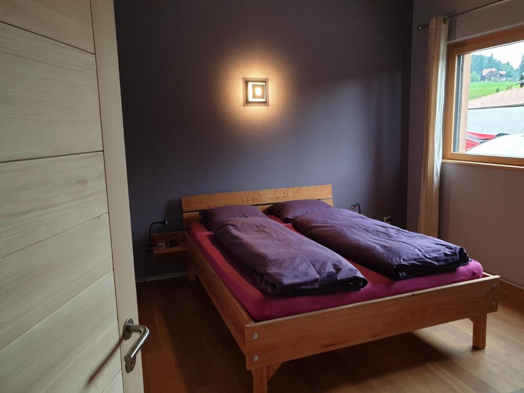 ein Schlafzimmer mit einem Bett mit lila Kissen darauf in der Unterkunft Gantrisch Lodge in Rüschegg