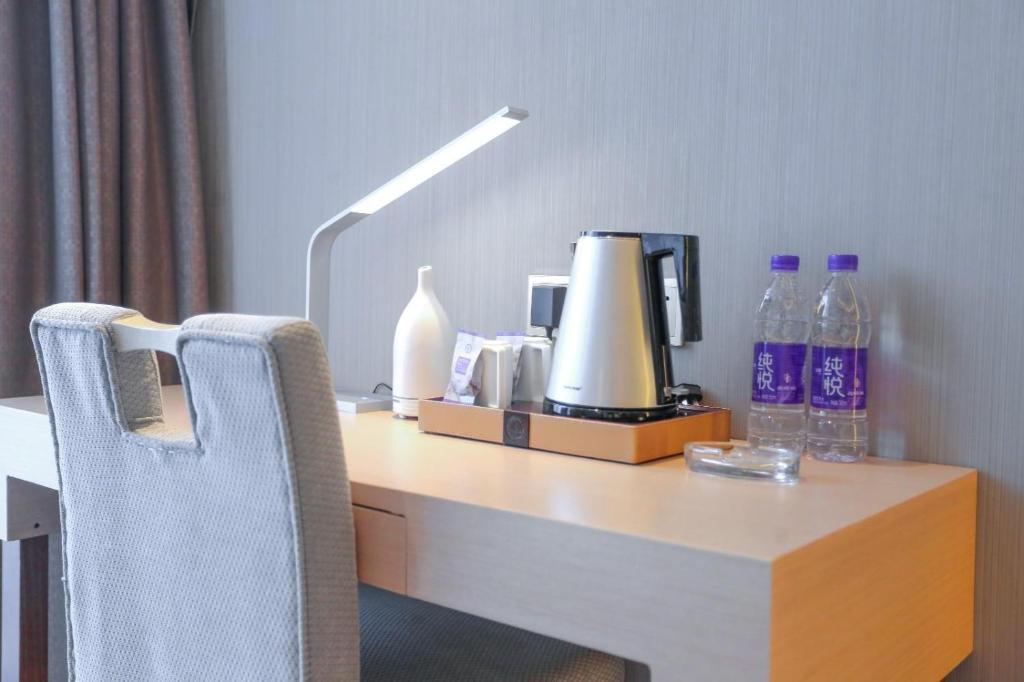 una scrivania con una sedia con lampada e bottiglie di Lavande Hotel Shijiazhuang Zhonghua North Street Zhongchu Plaza Branch a Shijiazhuang