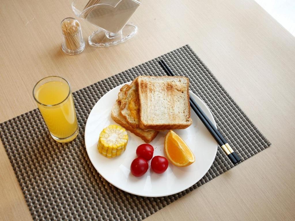 a plate of toast and fruit with a glass of orange juice at Lavande Hotel Jiujiang Jiujiang College in Jiujiang