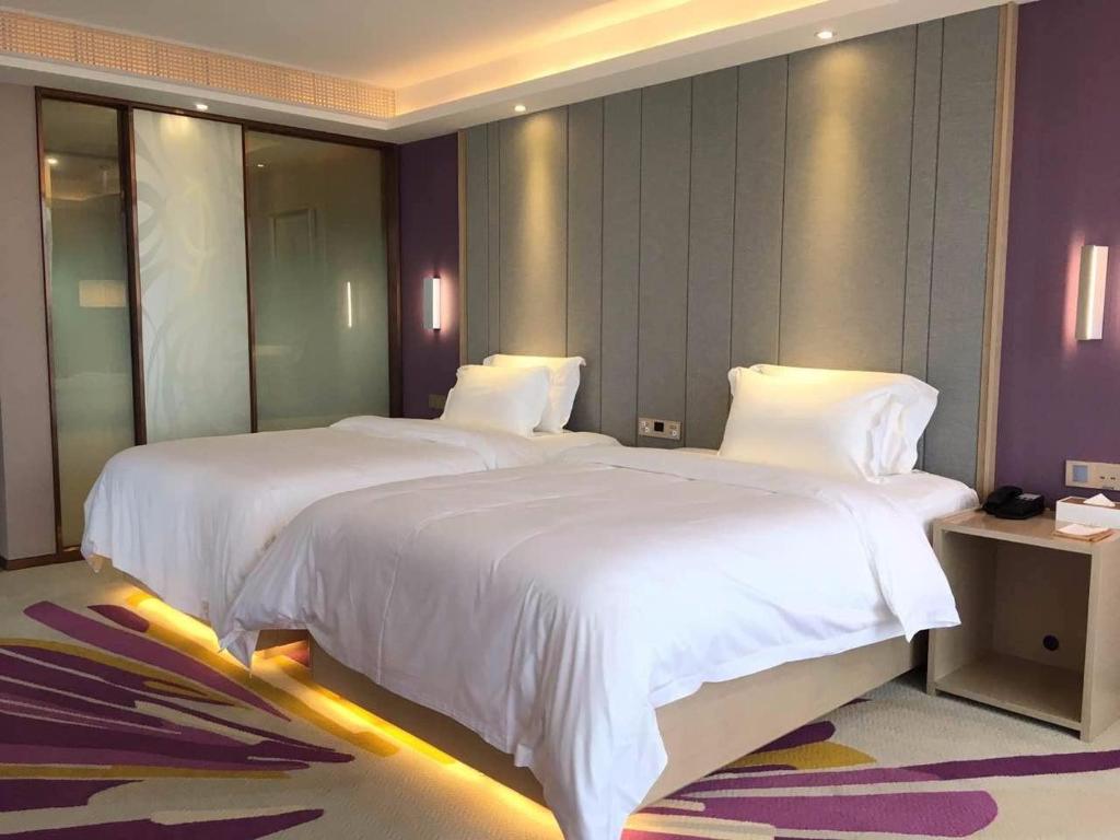 2 letti in camera d'albergo con lenzuola bianche di Lavande Hotel (Fuzhou Wanda Branch) a Fuzhou