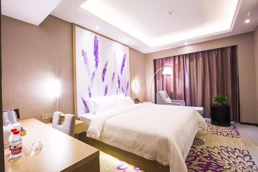 a hotel room with a large bed and a table at Lavande Hotel Xinyang Municipal Government Branch in Xinyang