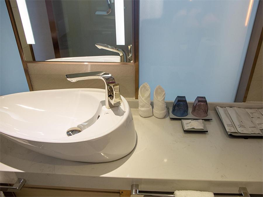Lavande Hotel Enshi Cultural Center في إنشي: بالوعة بيضاء في الحمام مع مرآة