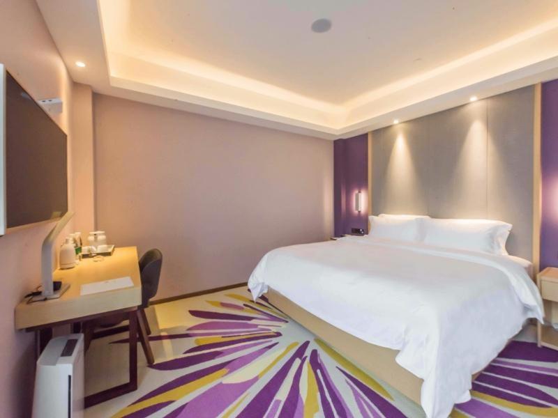a bedroom with a large white bed and a desk at Lavande Hotel Wuxi Taihu Avenue in Wuxi