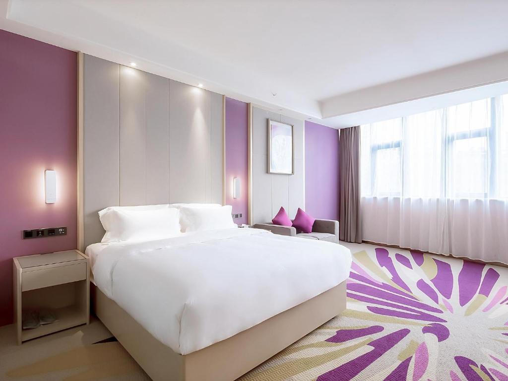 a bedroom with a large white bed and purple walls at Lavande Hotel Changsha Xingsha Center in Xingsha