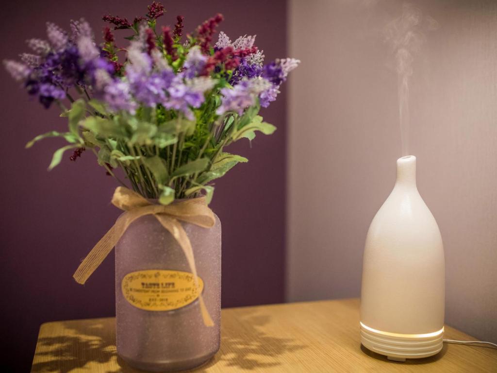 a table with a vase of purple flowers and a white bottle at Lavande Hotel (Binzhou Huanghe 8th Road, People's Hospital Branch) in Binzhou