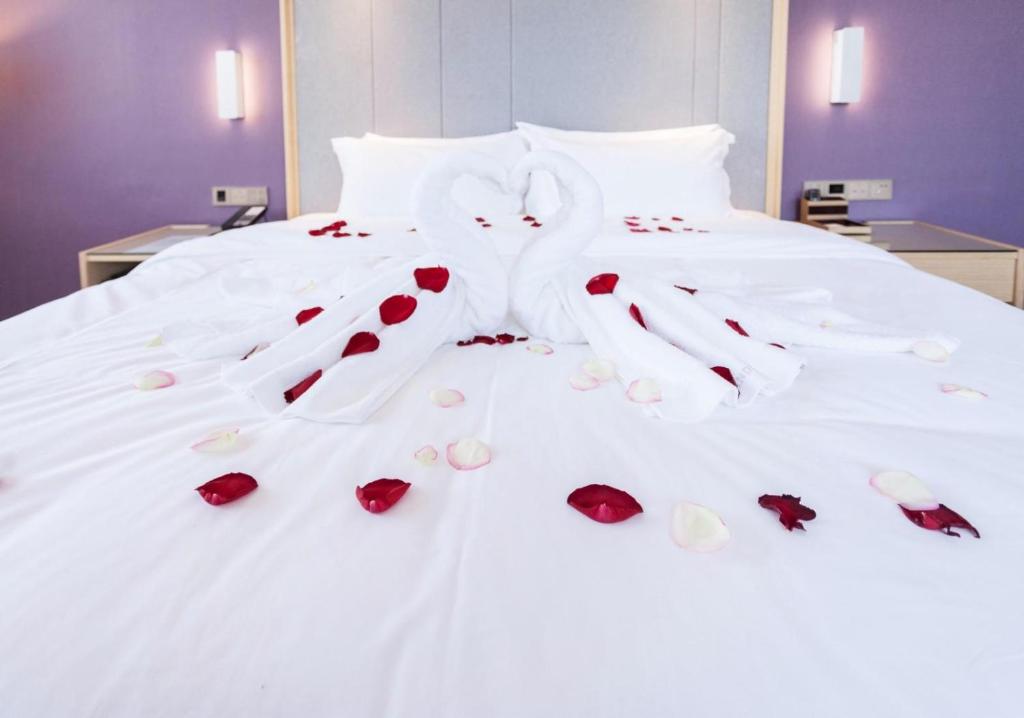 uma cama com rosas e luvas em Lavande Hotel Rizhao Xinshi District Branch em Rizhao