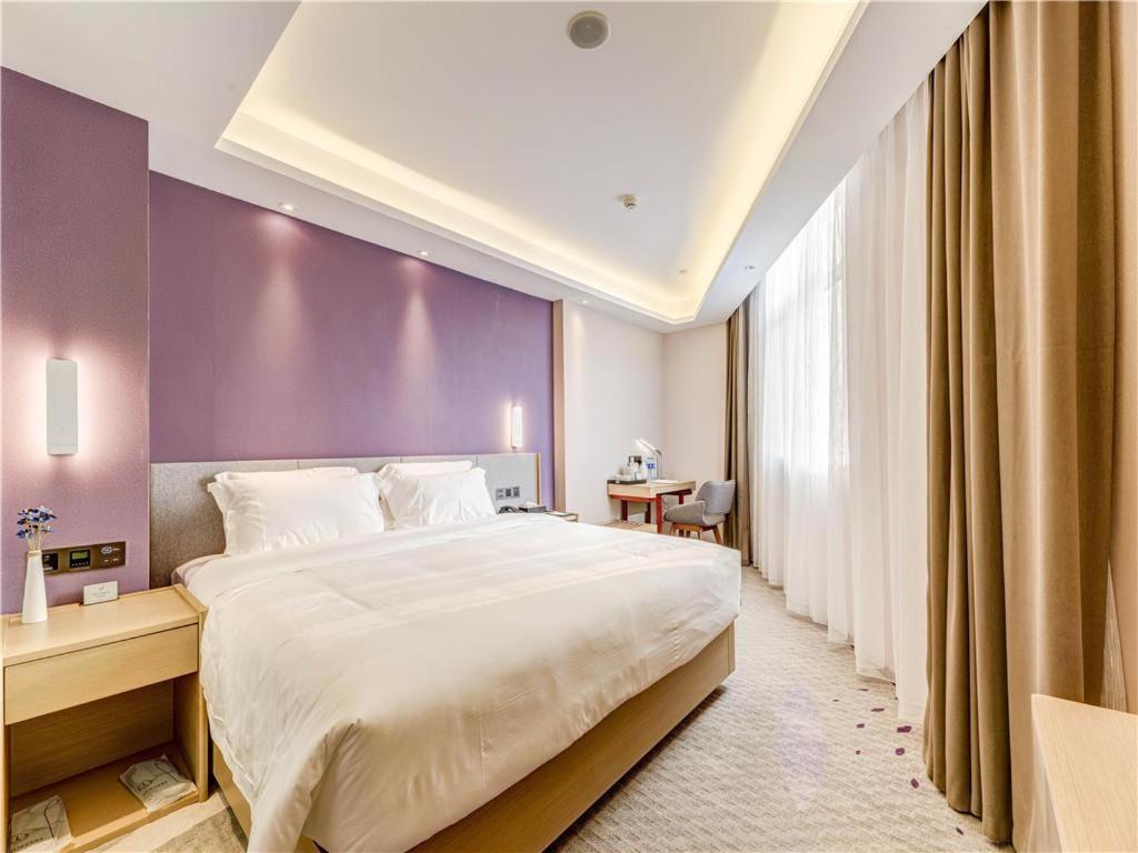 - une chambre avec un grand lit et un mur violet dans l'établissement Lavande Hotel Tangshan Convention and Exhibition Yuanyang City, à Tangshan