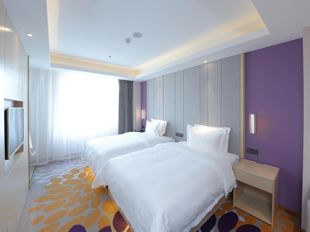 duas camas num quarto de hotel com paredes roxas em Lavande Hotel Changchun Hangkong University Fanrong Road Metro Station em Changchun