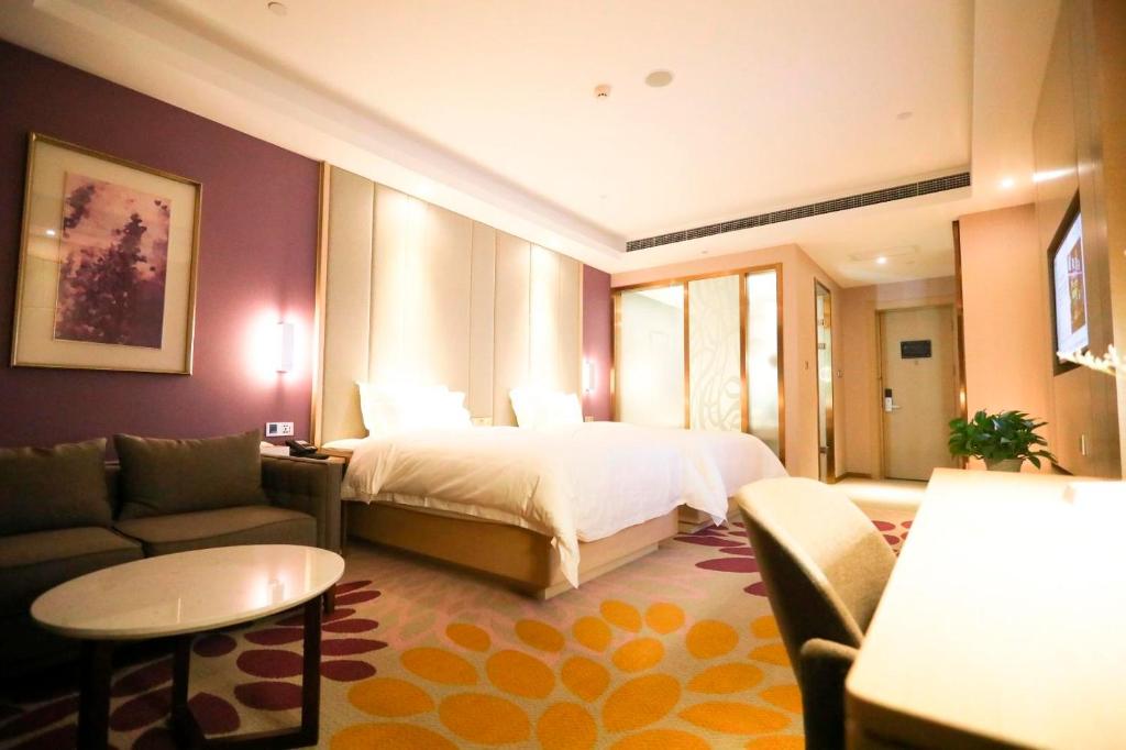 Lavande Hotel (Shijiazhuang Luquan Baoduzhai Beiguo Shopping Center Branch) في هيبي: غرفه فندقيه بسرير واريكه