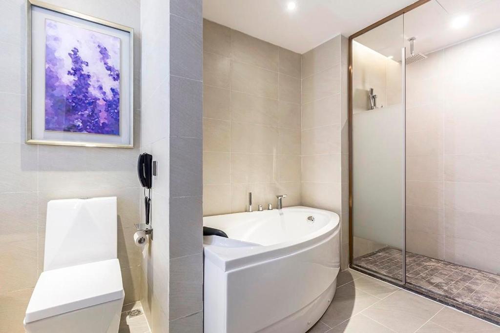 y baño blanco con bañera y ducha. en Lavande Hotel (Nanchang Liantang Xiaolan Industrial Park Branch), en Nanchang