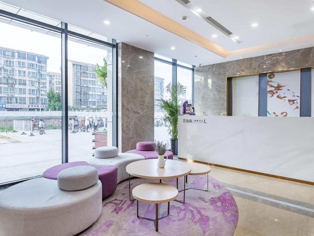 hol z fioletowymi krzesłami i stołami oraz dużym oknem w obiekcie Lavande Hotel Xuzhou Junsheng Plaza w mieście Xuzhou