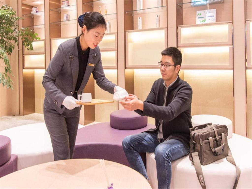 Una donna che consegna un piatto di cibo a un uomo di Lavande Hotel Xuzhou People's Square a Xuzhou