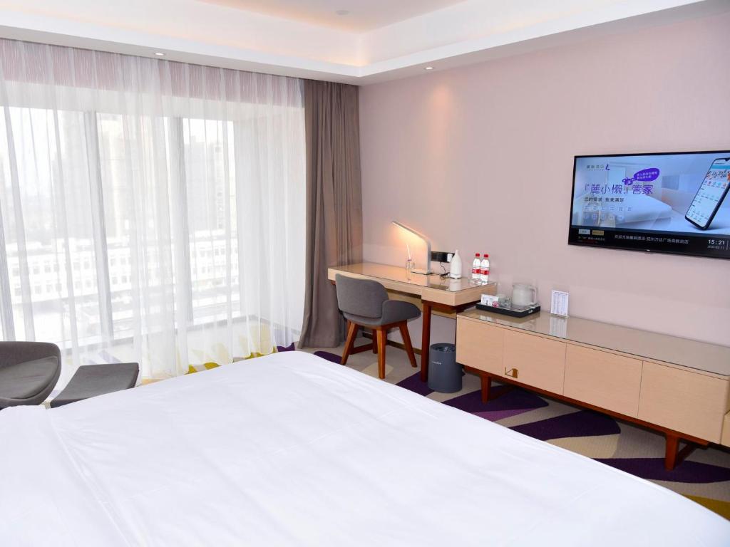 una camera d'albergo con letto, scrivania e TV di Lavande Hotel Fuzhou Wanda Plaza High-speed Railway Station a Fuzhou